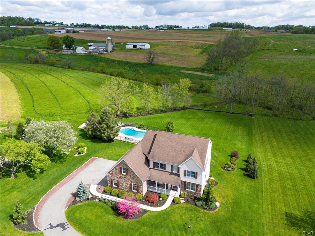 Drone view showing a home, pool, lawn, and surrounding countryside