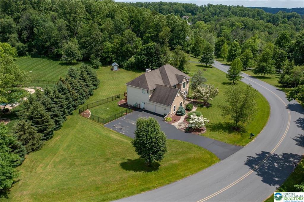Drone photograph showing a home’s driveway, yard, and tree-lined surroundings